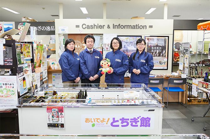 栃木県の観光と県産品の情報館「おいでよ！とちぎ館」にもステッカーが貼られている。写真に写っているのは左から店舗スタッフ2名と、栃木県の魅力をPRしている「とちぎおもてなしメイツ」2名
