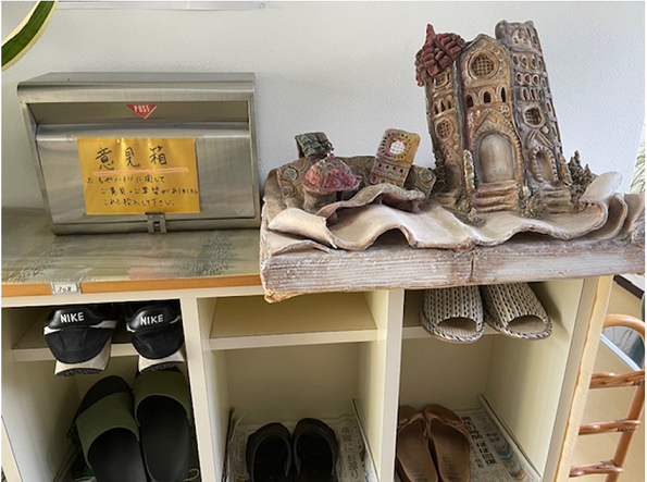 イメージ：下駄箱には北村オーナー自作の粘土細工とともに「意見箱」。入居者の要望を聞いて、賃貸経営のヒントに。下駄箱のスリッパの数は入居状況の目安。現在は満室です。